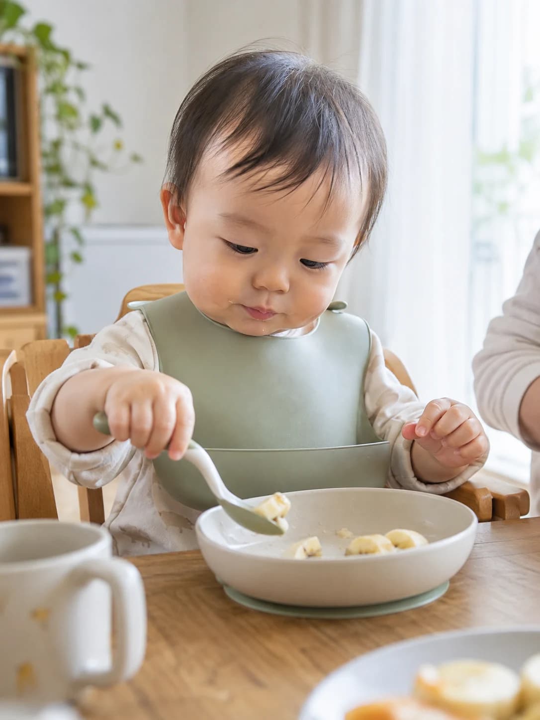 スプーンを持って朝ごはんを食べる赤ちゃん