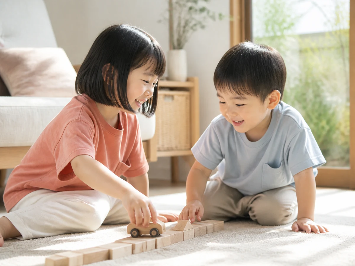 積み木の道に車を走らせながら笑い合うきょうだい